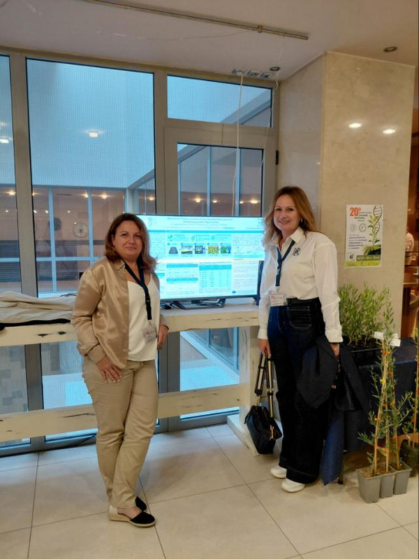 Two women standing in front of a computer screen.