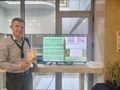 A man standing next to a computer screen.