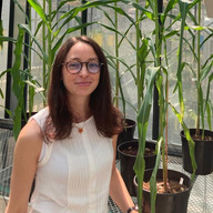 Giulia Castorina standing in a greenhouse with plants behind her.